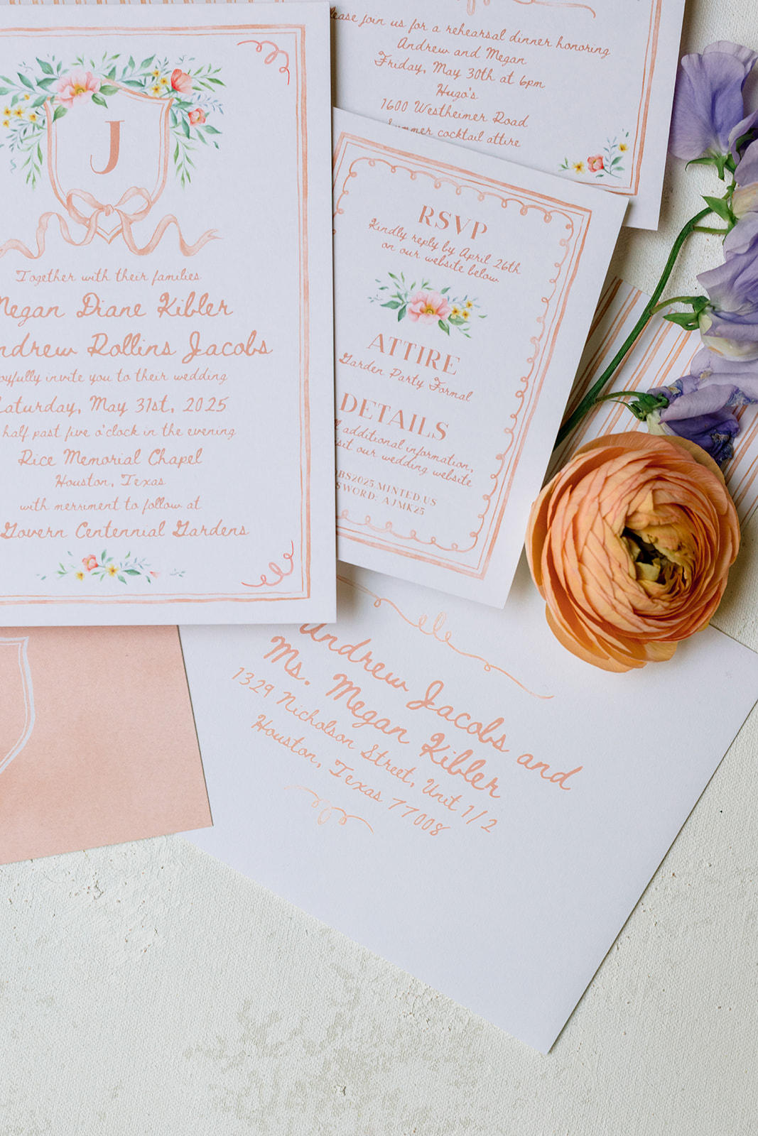 Two green velvet ring boxes with wedding rings, surrounded by wedding invitations and pastel flowers on a light surface.