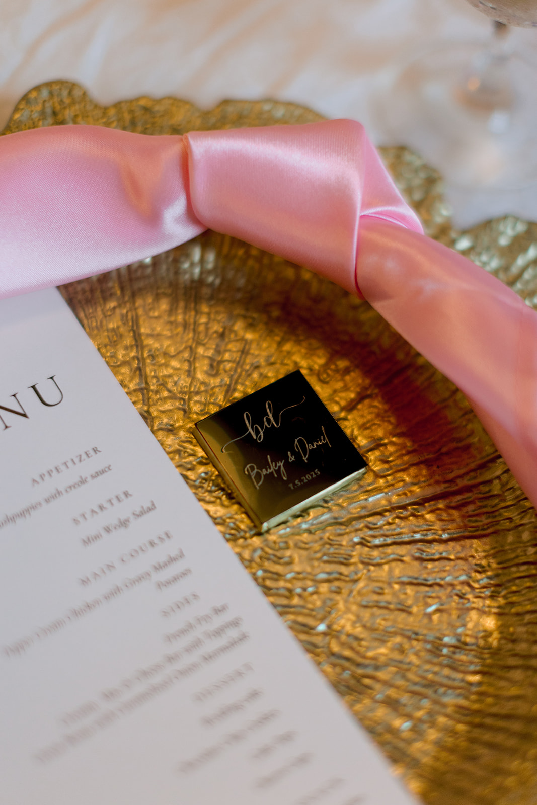 A round table set for an event with pink napkins, glassware, floating candles in vases, and a table number card reading “10.”. for a sandlewood manor wedding