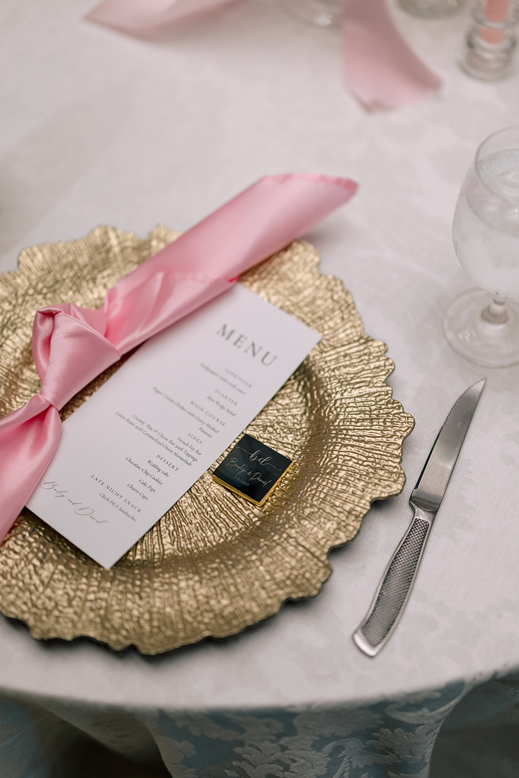 A three-tiered white cake with two small dog figurines, one brown and one beige, sits on a silver tray.