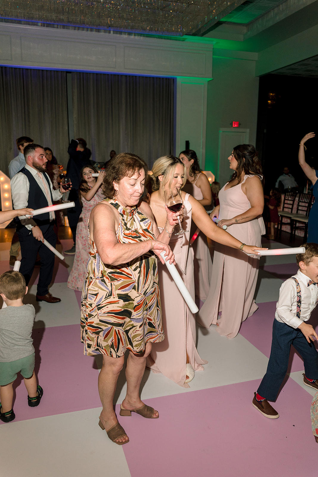 a group of people dance on a pink checkered floor at a celebration