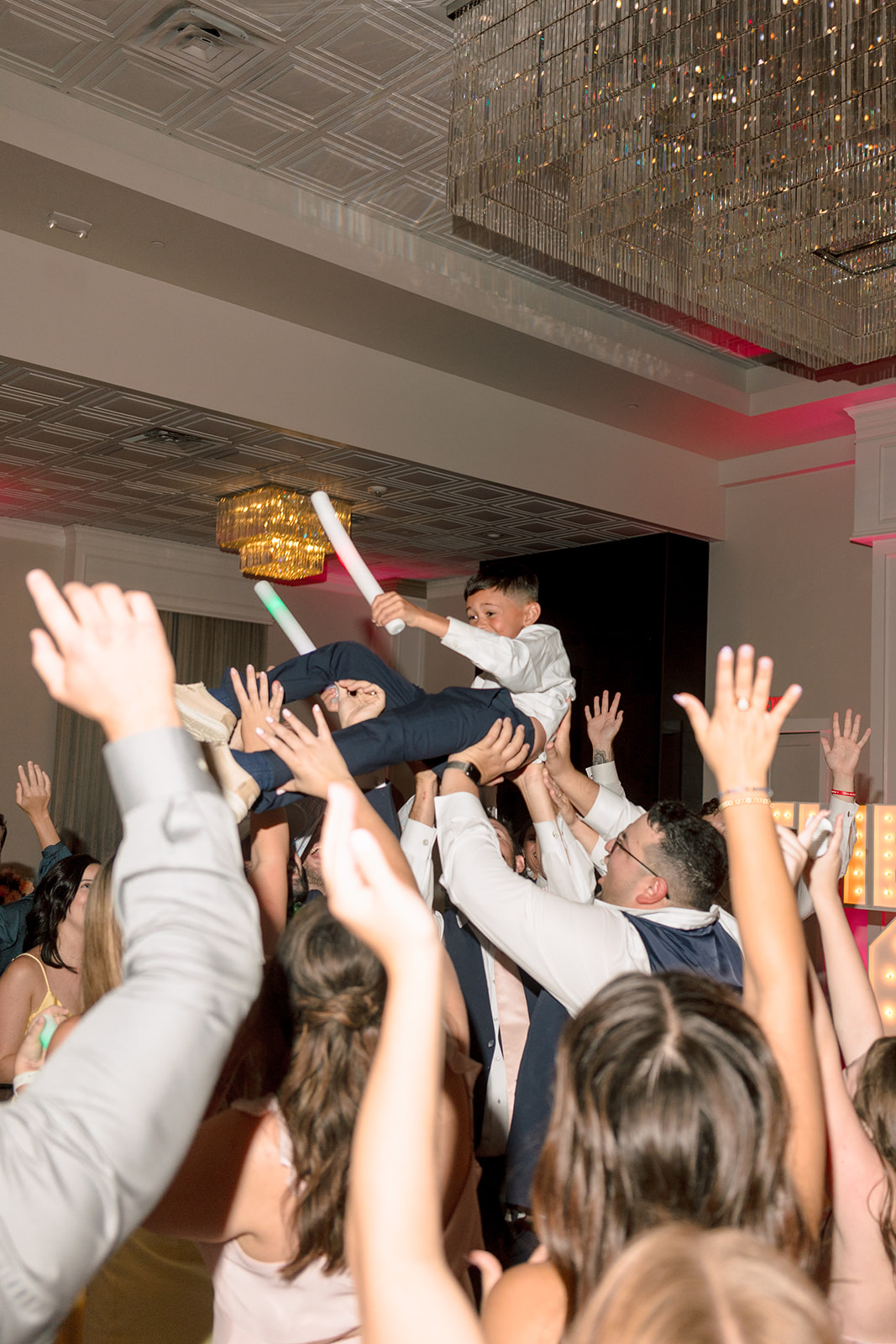 a group of people dance on a pink checkered floor at a celebration