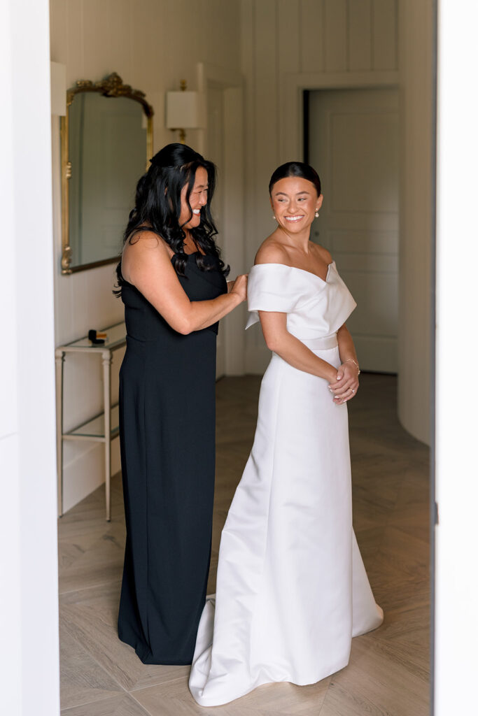 mother of the bride helping her with the wedding dress
