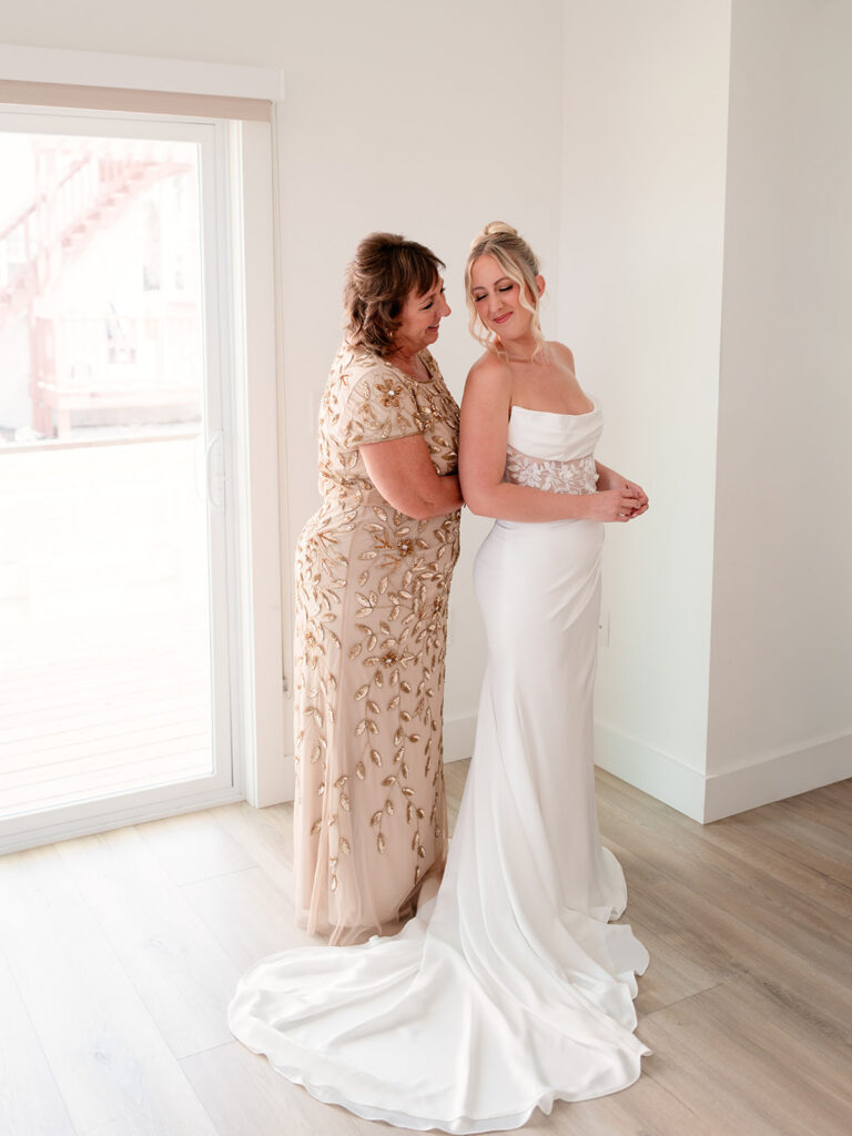 Mother of the bride helping her with the wedding dress