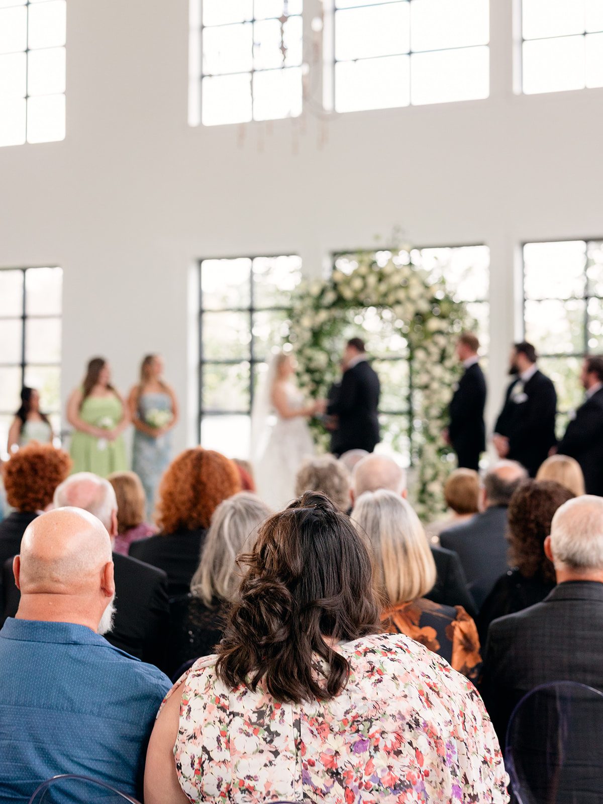 Indoor ceremony under florals and chandeliers at Boxwood Manor by Aly Matei Photography