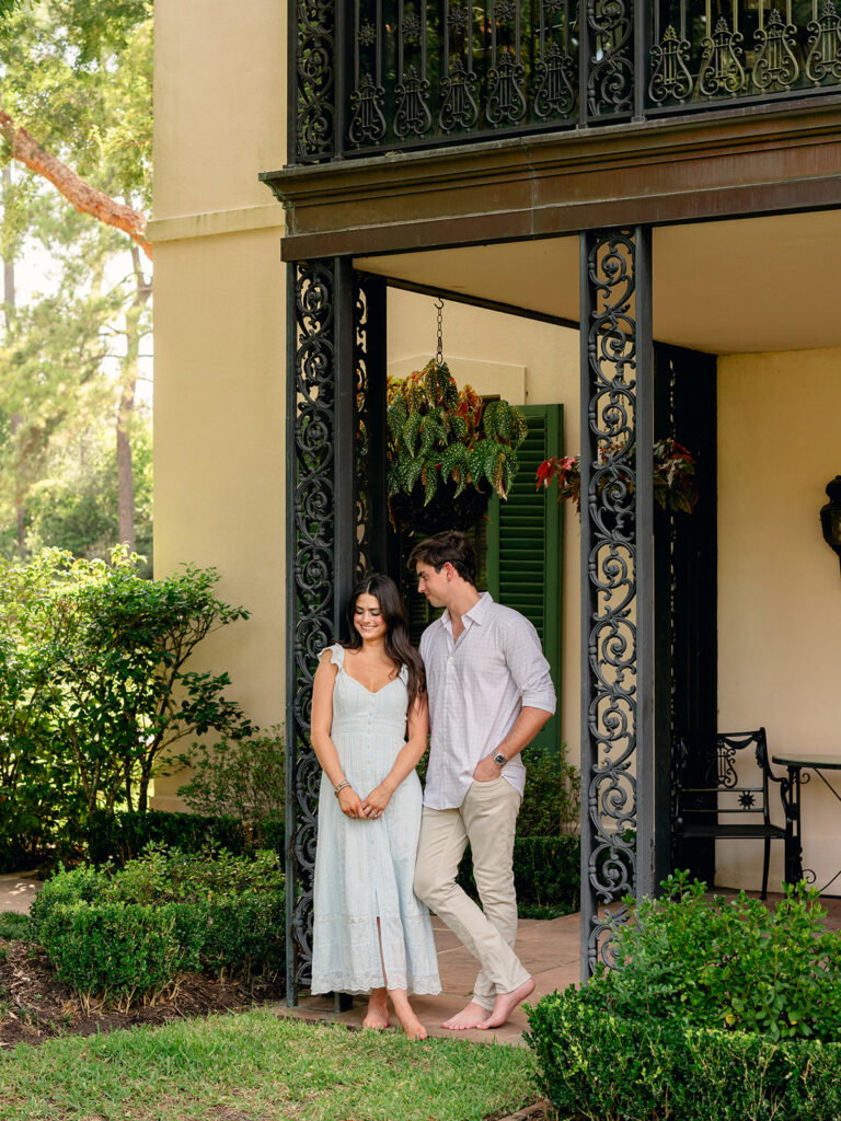 Candid moment between the engaged couple under the wrought iron porch at Bayou Bend Collection and Gardens
