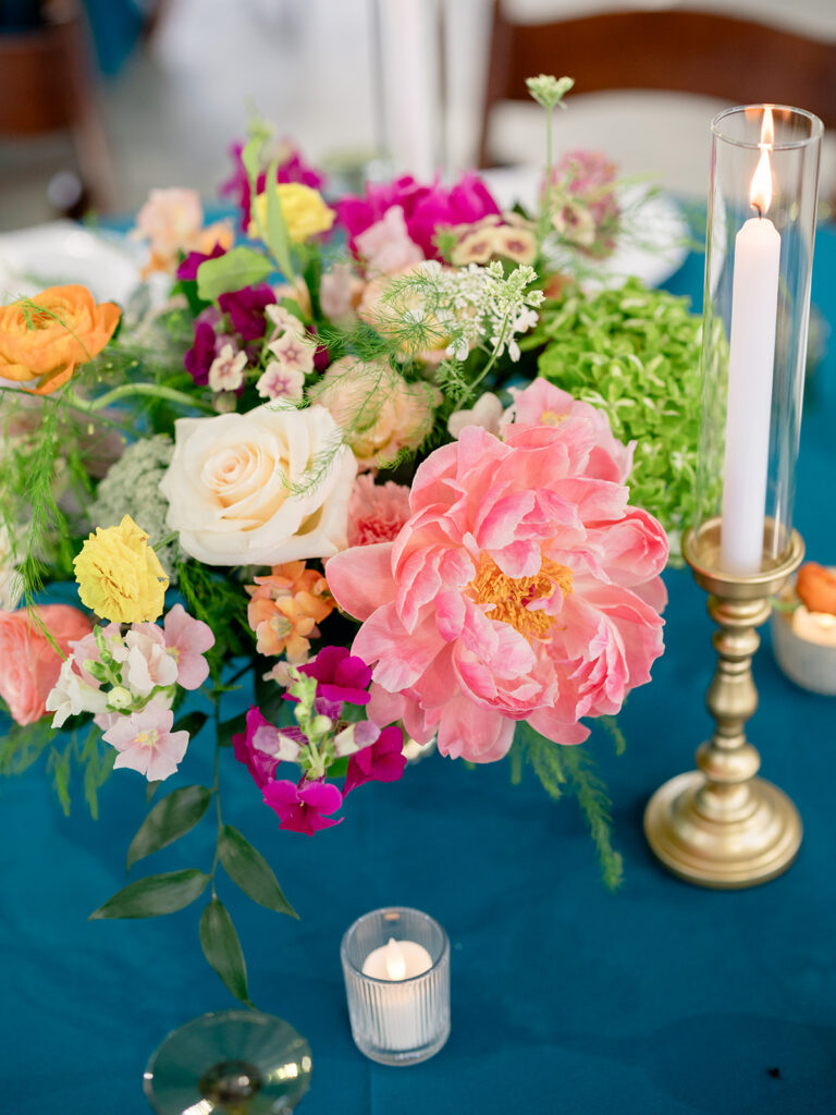 Coral peony centerpiece with gold candlesticks at the rehearsal dinner