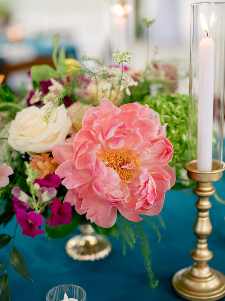 Colorful rehearsal dinner centerpiece with coral peonies and taper candles