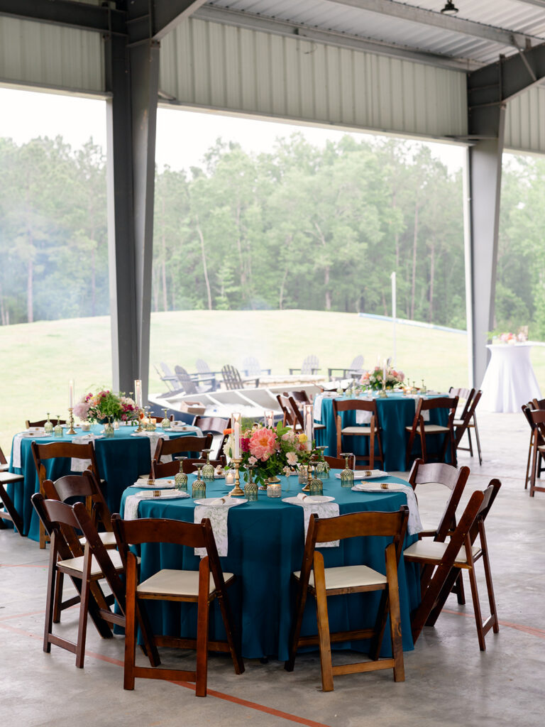 Rehearsal dinner tables with teal linens and a view of the camp lake