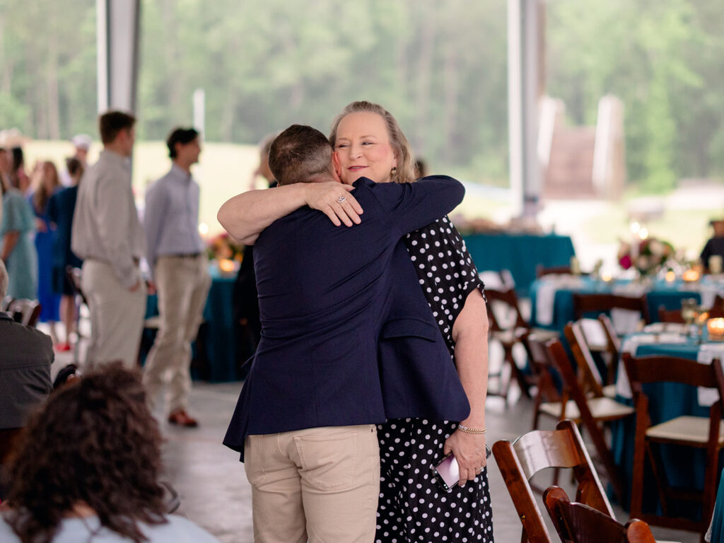 Groom hugging a guest at the rehearsal dinner pavilion