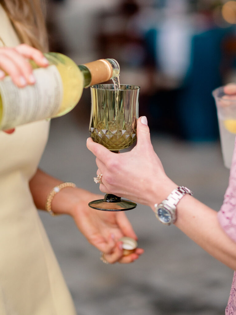Wine being poured into a green crystal glass at the rehearsal dinner