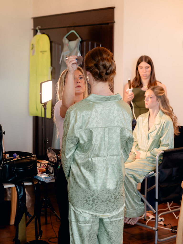 Bridesmaids in sage pajamas in the getting ready suite
