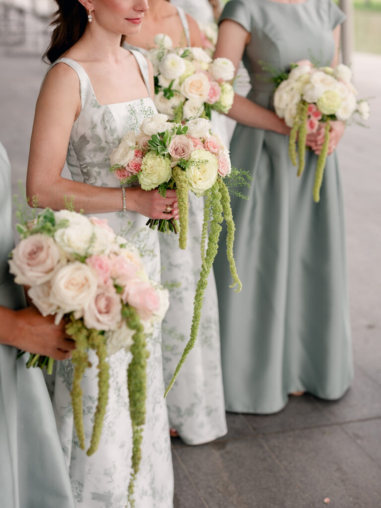Bridesmaids holding blush and ivory rose bouquets with trailing amaranthus