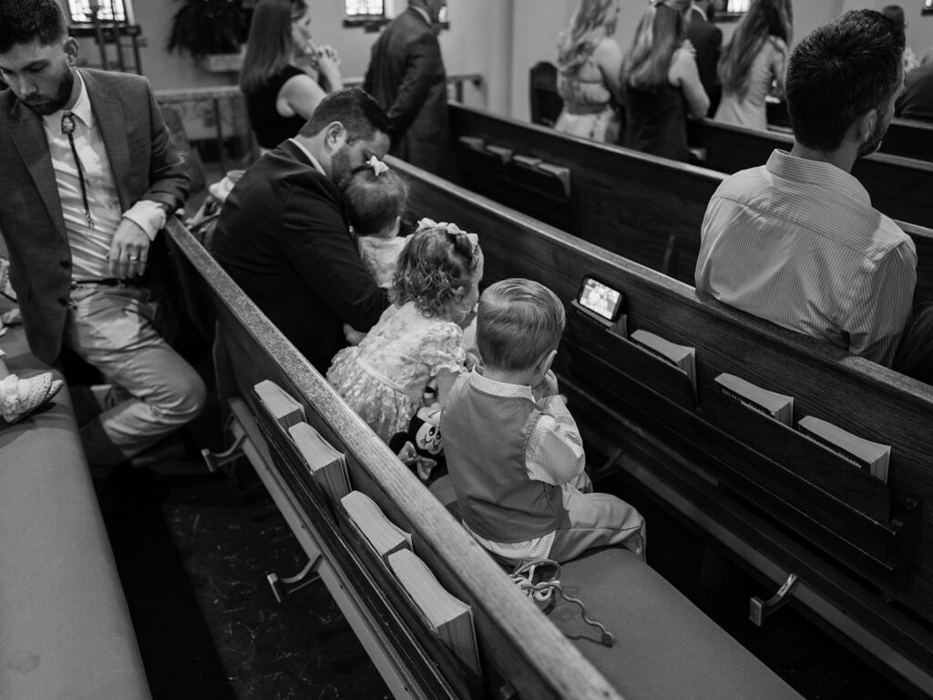 Black and white photo of kids waiting in the church pews