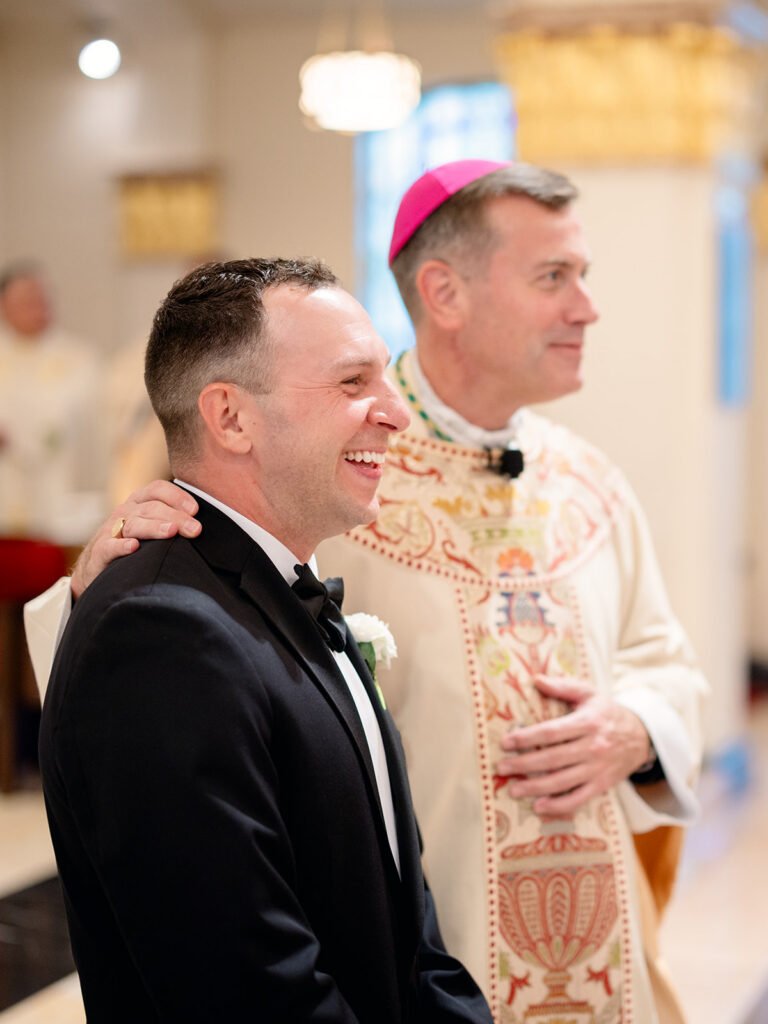 Groom laughing with the bishop before the ceremony