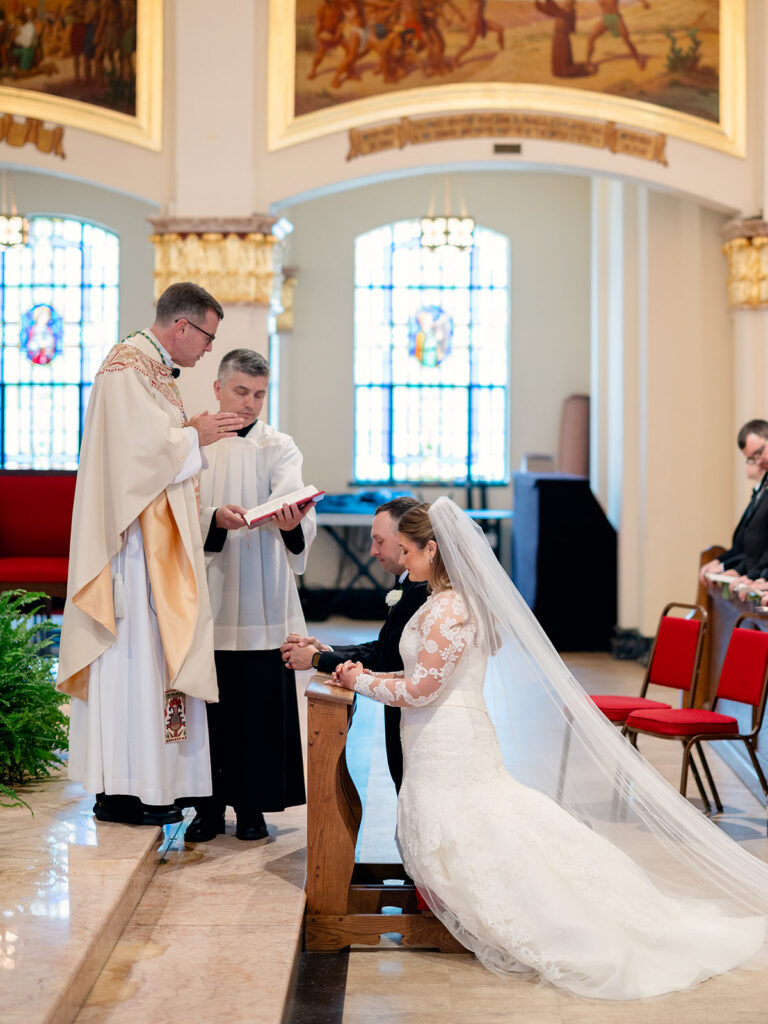 Bride and groom kneeling for a blessing during the wedding mass