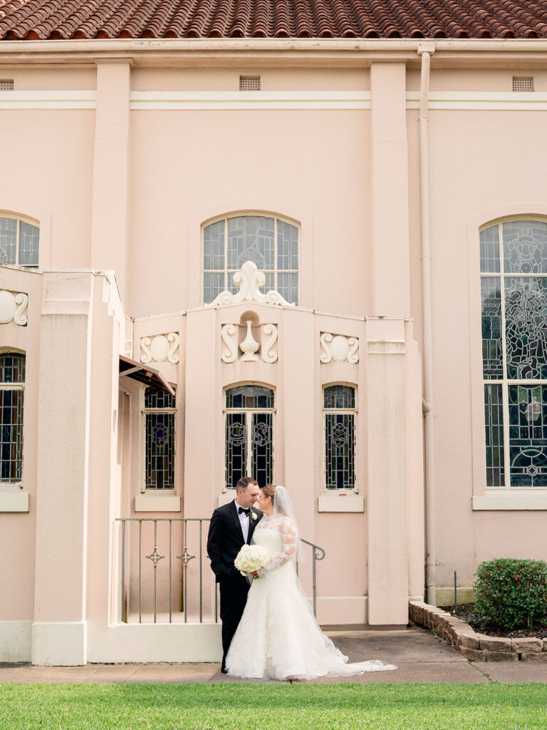 Bride and groom in front of the pink stucco church
