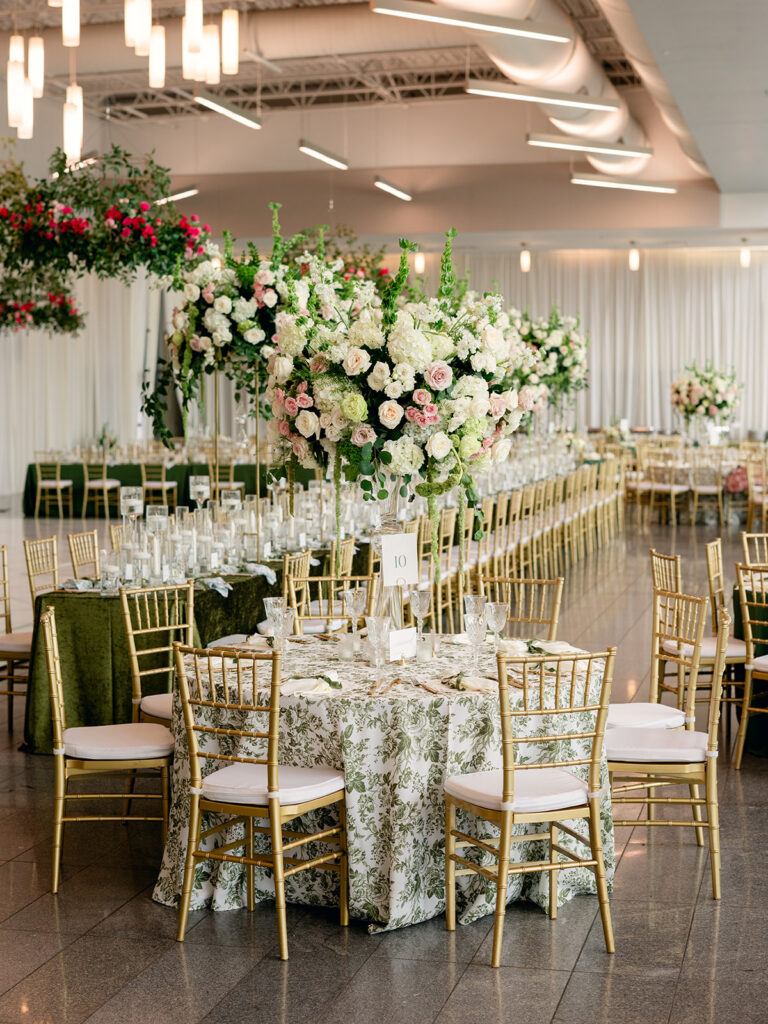 Reception hall with tall floral centerpieces and gold chairs