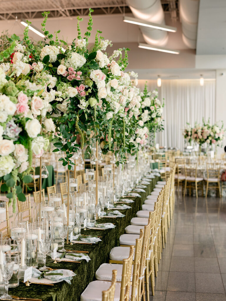 Long reception table under towering white and blush florals