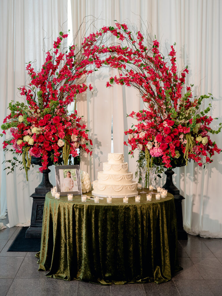 Wedding cake table with a red floral arch