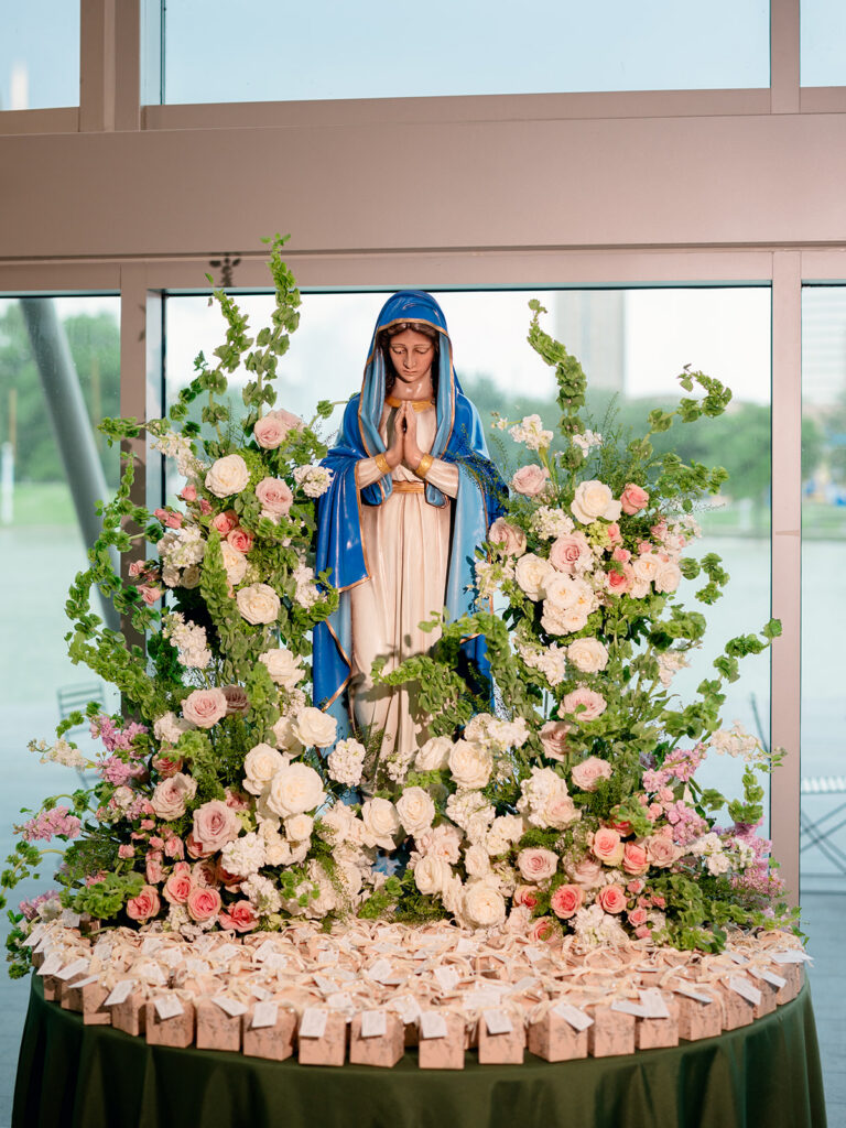 Virgin Mary statue surrounded by roses and garden florals at the reception