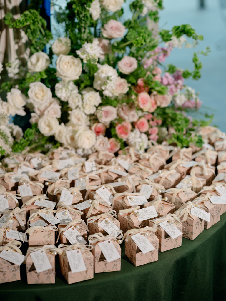 Rows of wedding favors beneath pink and white florals