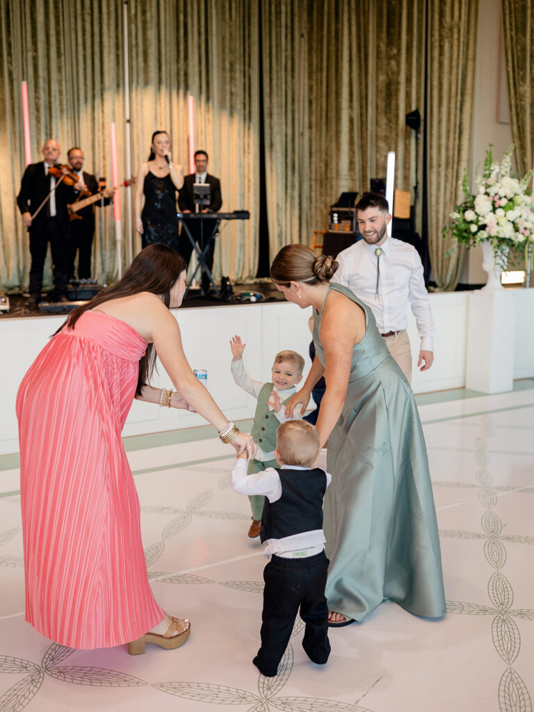 Bridesmaids dancing with toddlers in front of the band