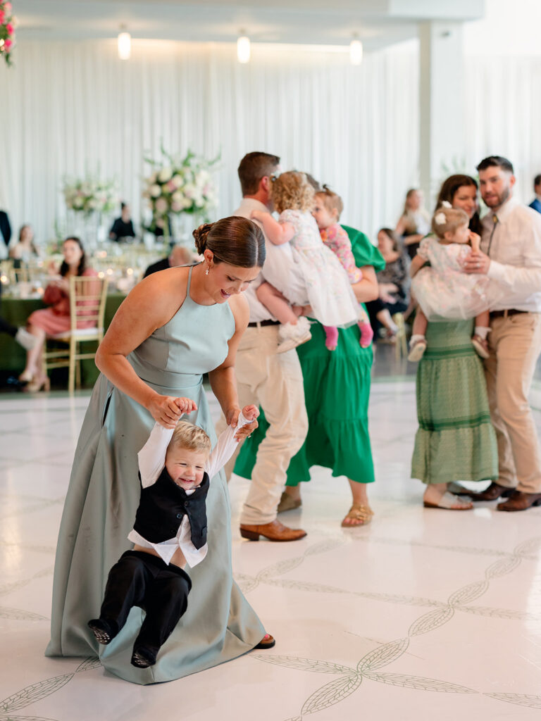 Bridesmaid swinging a toddler on the dance floor