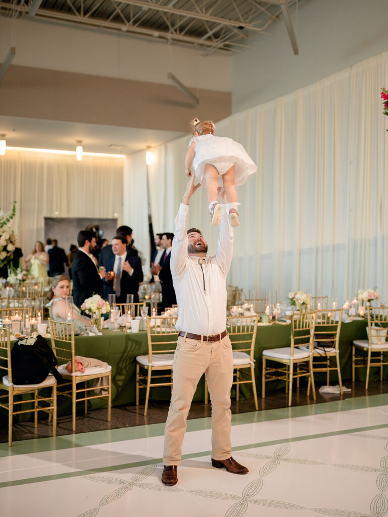 Guest lifting a toddler over his head on the dance floor