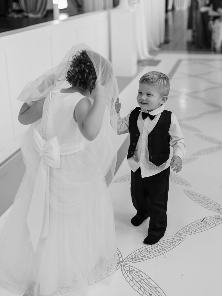 Black and white photo of a little girl in a veil dancing with a little boy